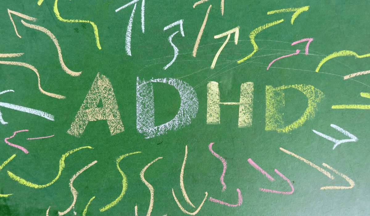 Colorful chalk-drawn ADHD letters surrounded by scattered arrows, symbolizing focus difficulties and hyperactivity.